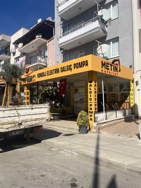 Metin Yapı'nın köşe konumundaki dış cephesi ve sarı sondaj, elektrik, dalgıç pompa tabelası
